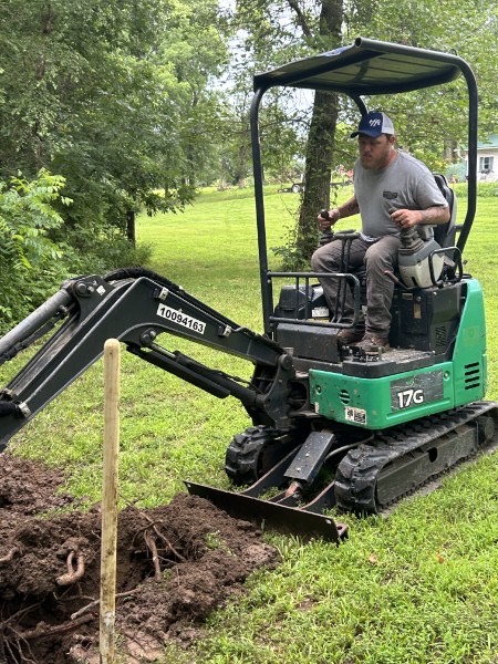 Hometown Flow Plumbing owner running a mini-excavator on a sewer job near Nevada, MO